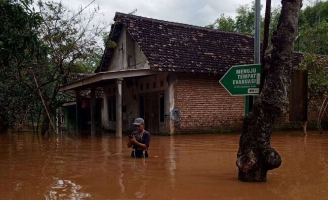 
					Salah seorang warga tengah menerjang banjir yang memasuki pemukimannya, Selasa (1/4/2025) sore. Ia bahkan mengabadikan momen tersebut. (Foto : BPBD Kabupaten Pasuruan)